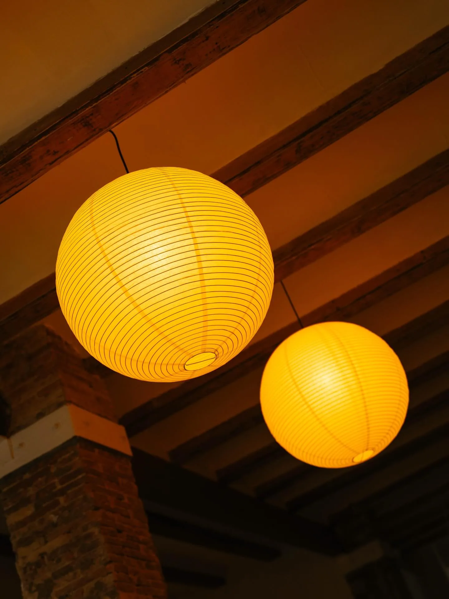 Lámparas cálidas iluminando las vigas de Casa Lenta